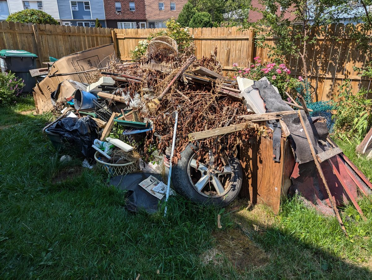 Mixed debris and old shed material before a backyard cleanout in Middletown, New York
