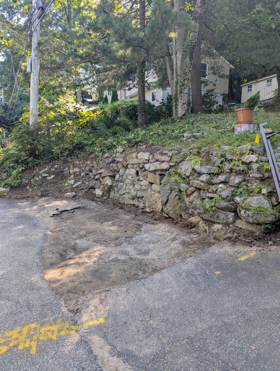 Cleared stone-lined driveway edge after brush removal in Ringwood, New Jersey